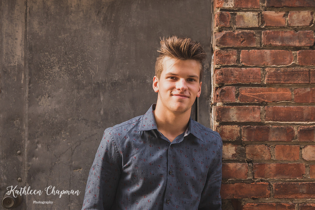 Senior boy smiling in alley near brick wall in Massena, NY Potsdam child photographer