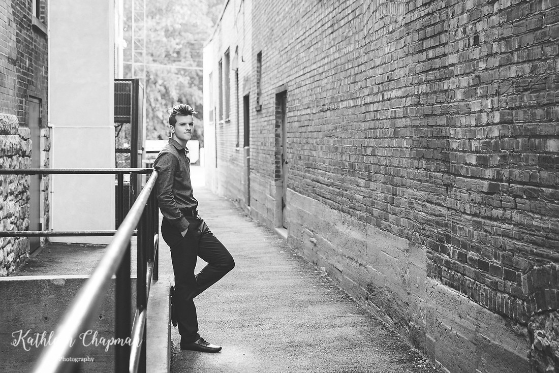 Senior boy leaning on railing in brick alley in Massena NY Potsdam child photographer