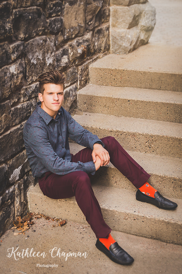 Senior guy with serious expression on steps in brick alley in Massena NY Potsdam child photographer