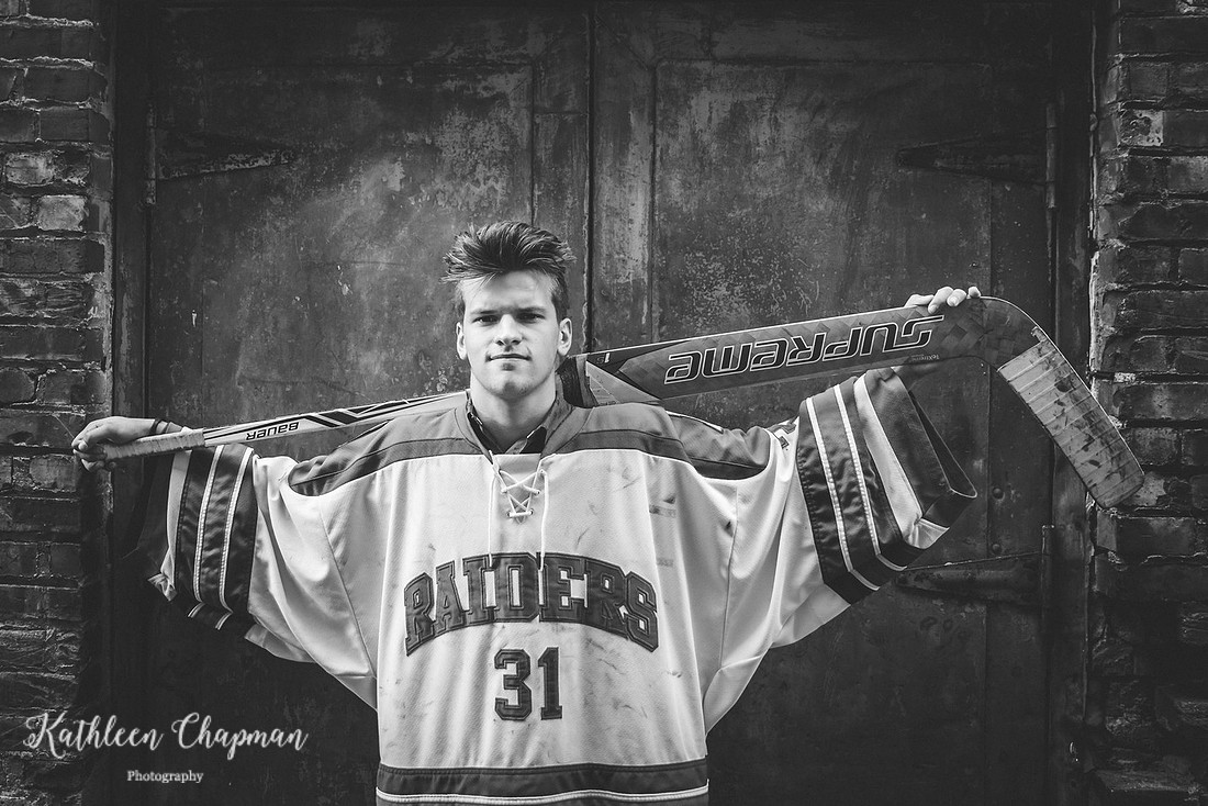 Senior boy in hockey jersey in brick alley in Potsdam NY St. Lawrence County family photographer