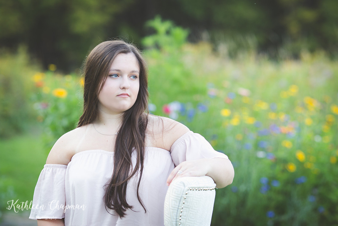 Beautiful senior girl in chair in wild flower garden malone ny senior photographer
