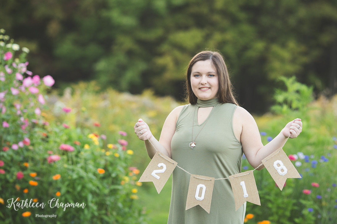 senior girl holding 2018 banner in wild flower garden franklin county family photographer