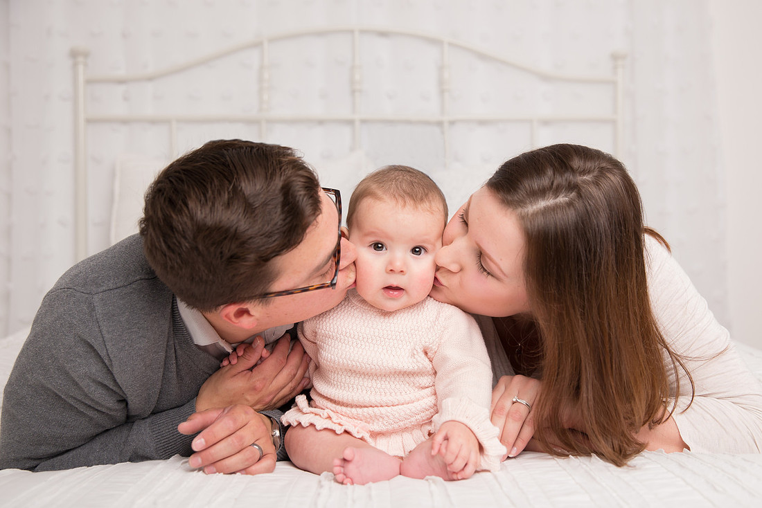 parents kissing baby girl on cheeks potsdam ny child photographer